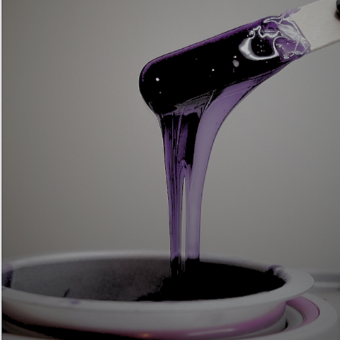 Purple tar-like substance pouring from a spatula into a bowl.
