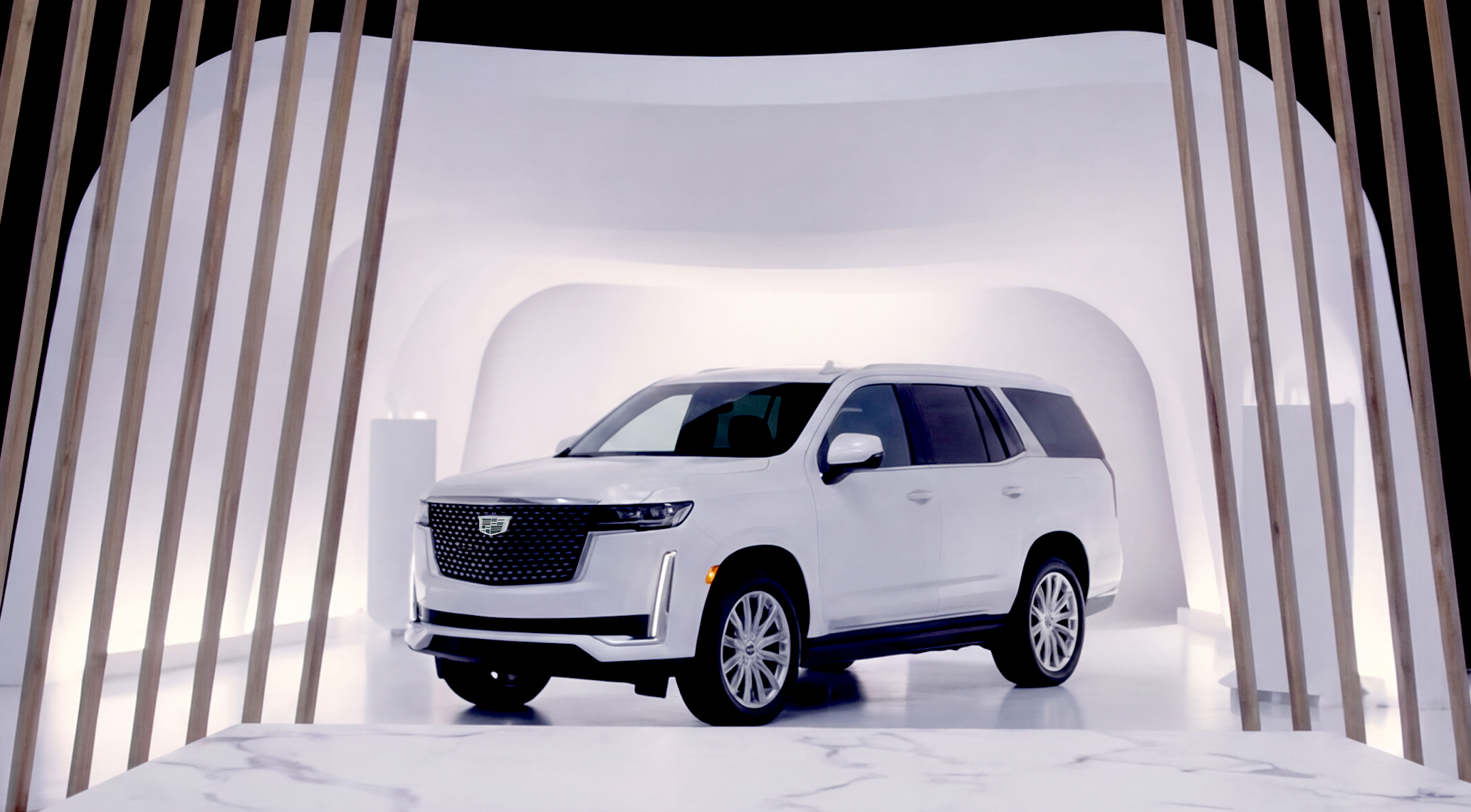 White Cadillac Escalade SUV vehicle on display in Cadillac Live's showroom.