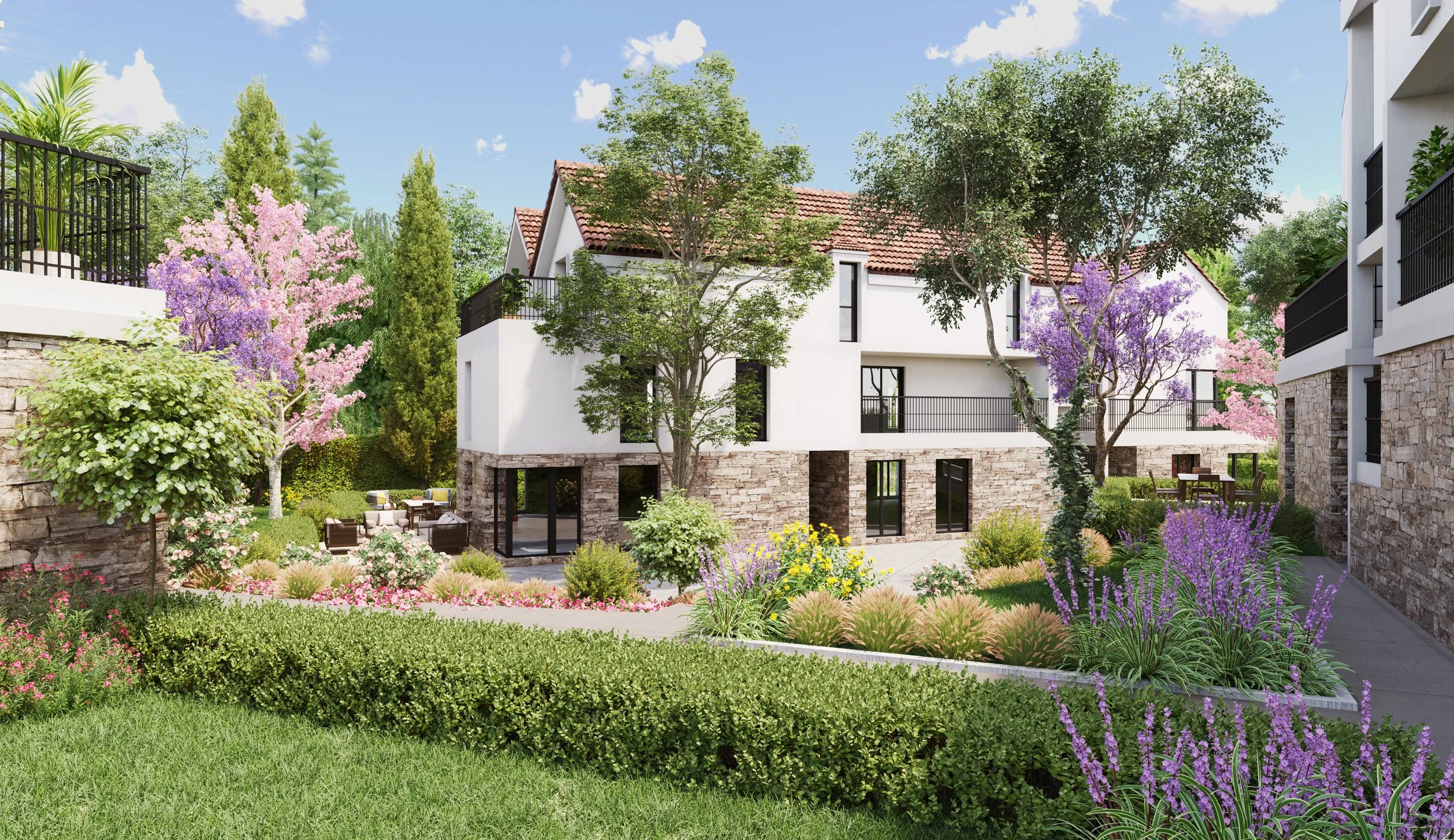 Coeur d'ilot Domaine les Arômes | Appartement moderne avec jardin fleuri et arbres, terrasse avec mobilier, bâtiments en pierre et blanc, ciel bleu avec quelques nuages