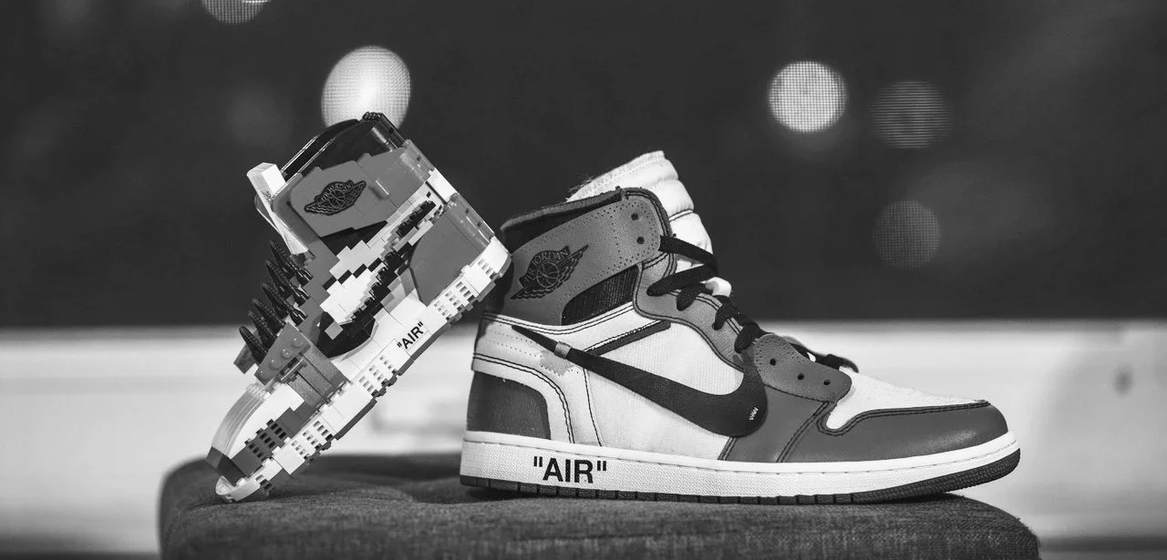 Chaussure de sport de type sneakers avec design inspiré de Lego, noir et blanc, avec le mot 'AIR' écrit sur la semelle.