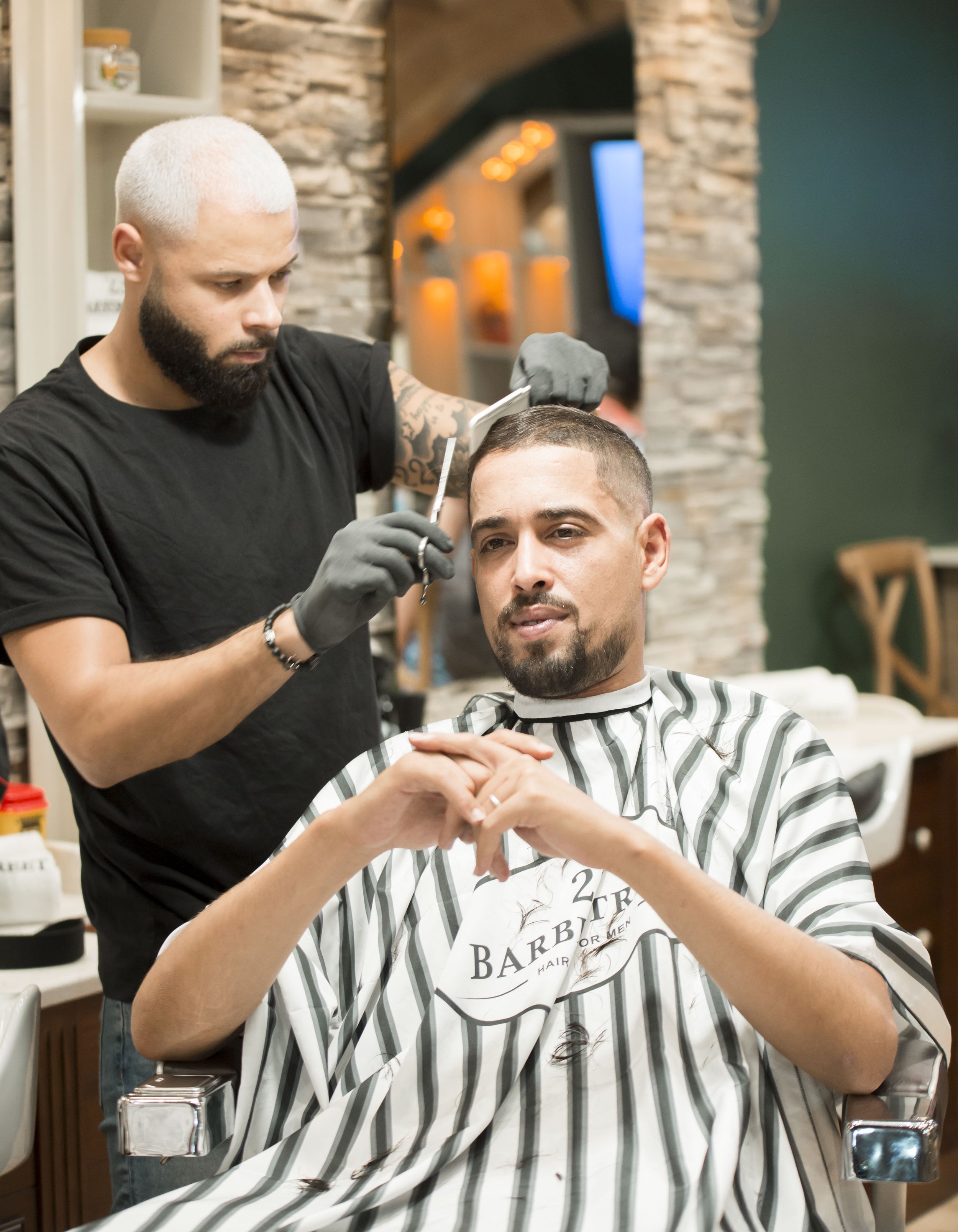 Homme en salon de coiffure recevant une coupe de cheveux, coiffeur utilisant des ciseaux et une tondeuse, salon avec décoration chaleureuse.
Best barber shop salon de coiffure Marrakech