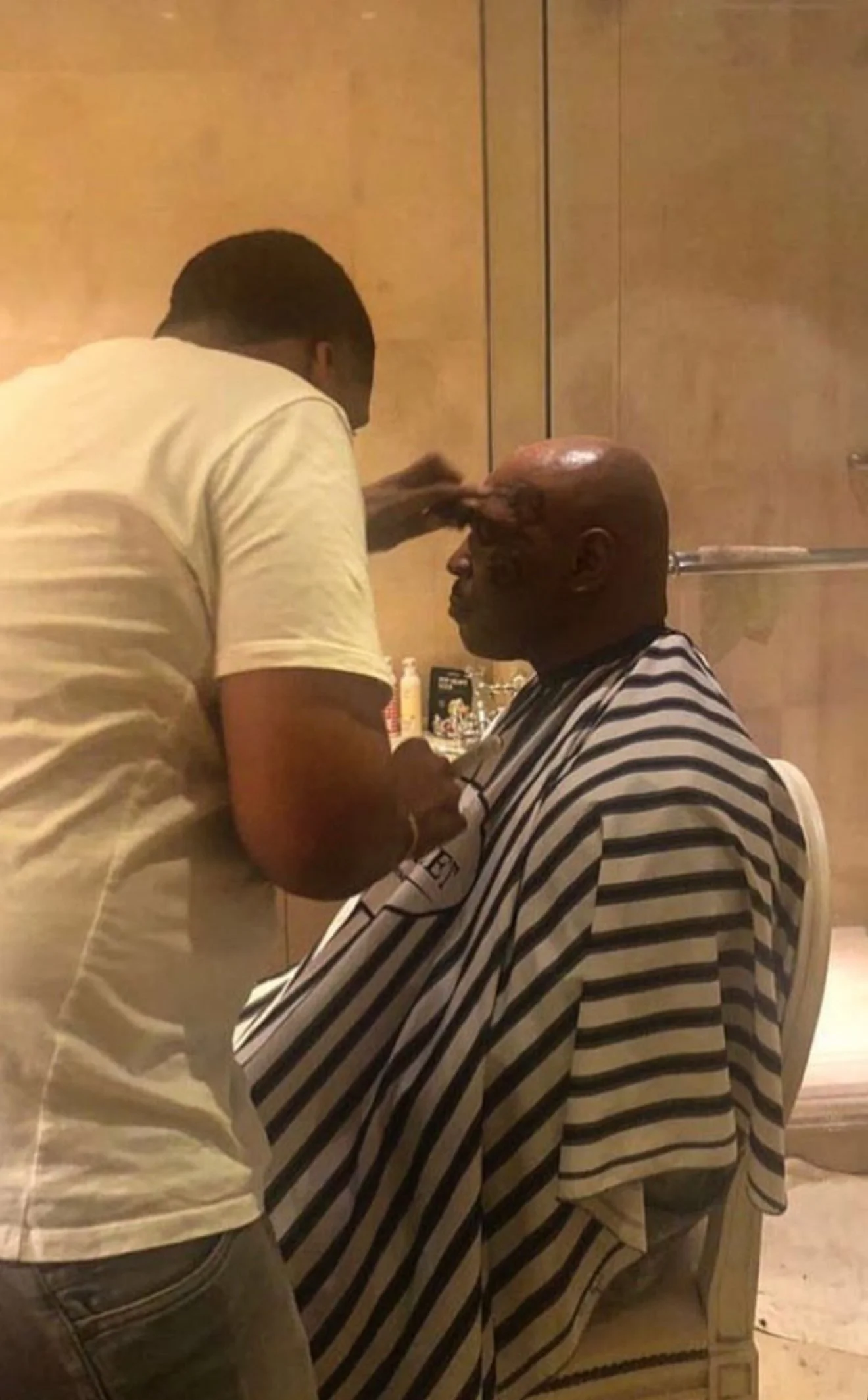 Une personne couverte de cicatrices reçoit une coupe de cheveux dans un salon de coiffure. Best barber shop salon de coiffure Marrakech