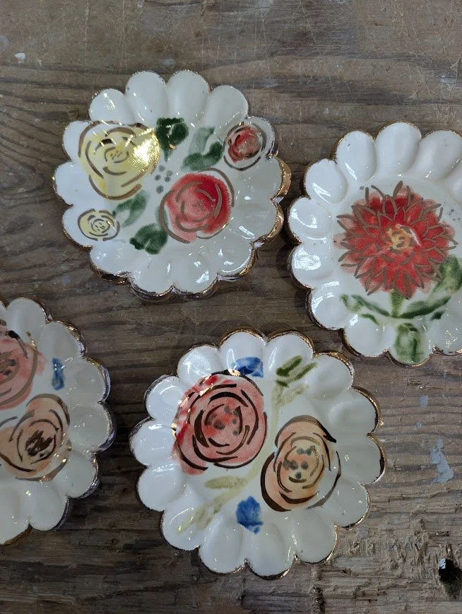Decorative flower-shaped porcelain dish with hand-painted floral designs, placed on a wooden surface.