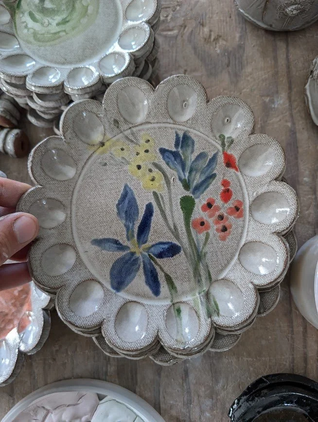 Decorative ceramic or porcelain plate with a hand-painted floral design, surrounded by small matching dishes.