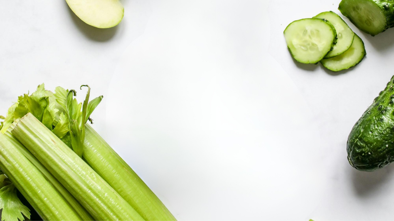 Fresh green celery stalks, cucumber slices, and a whole cucumber on a white background.