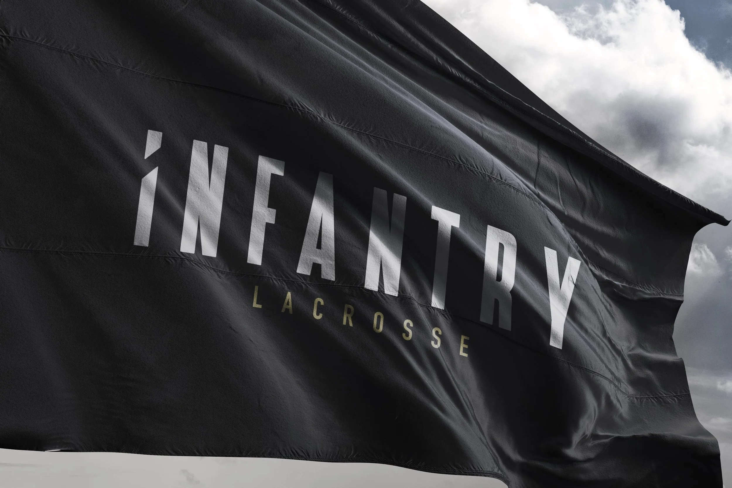 Black flag with "Infantry Lacrosse" logo against a cloudy sky.