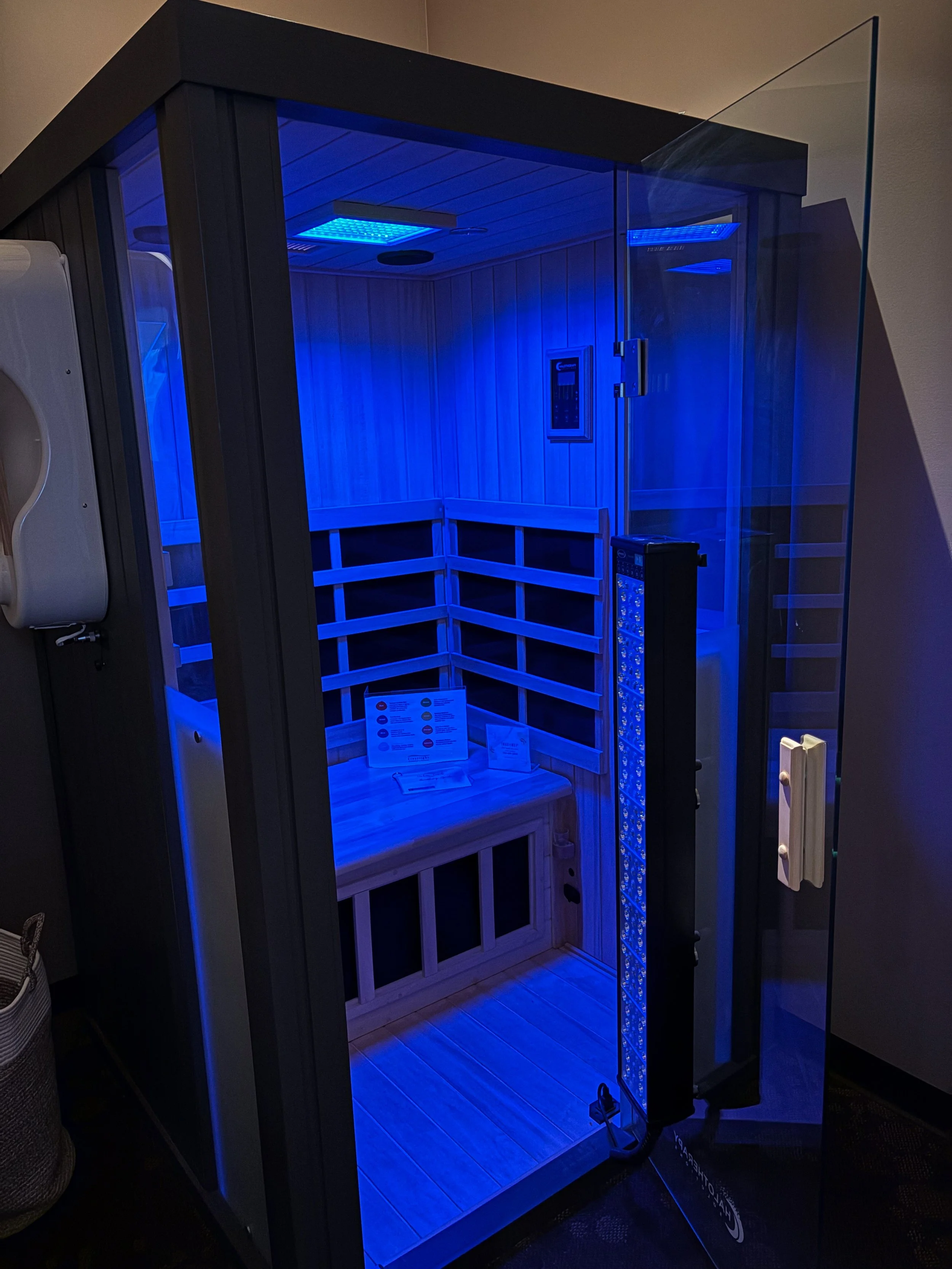 A modern infrared sauna with wooden interior illuminated by blue LED lights.