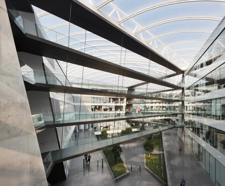 Modernes, multi-geschossiges Atrium mit Glaswänden und einer hohen, gewölbten Decke aus Glas