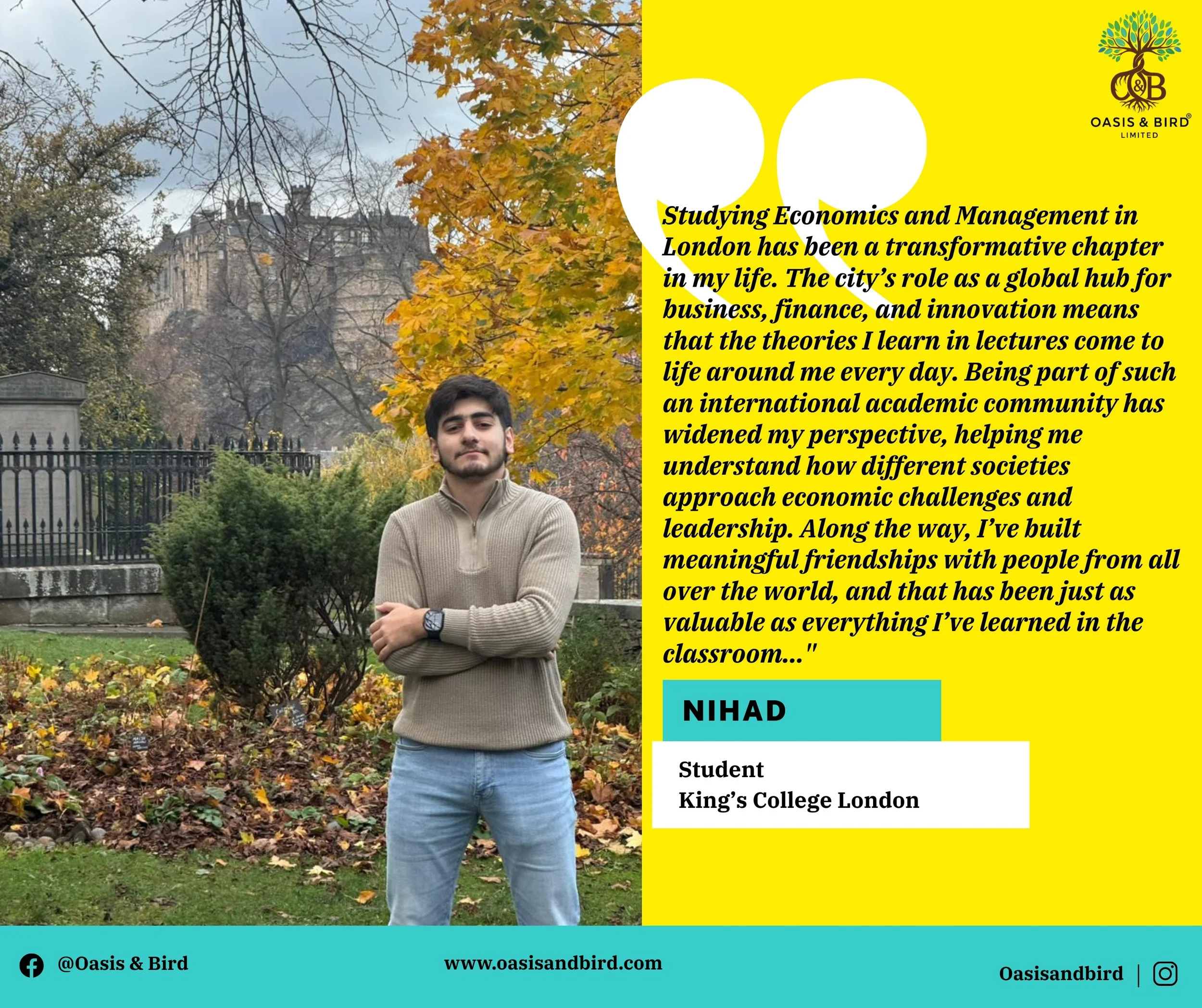 A young man standing outdoors in a park during autumn, with trees that have colorful fall foliage and a castle-like building in the background. He is wearing a beige sweater, blue jeans, and a watch, with his arms crossed.
