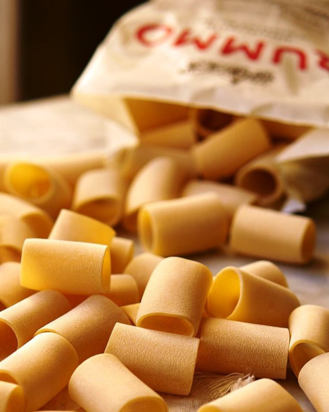 Pasta shells spilled from a partially open bag onto a surface.