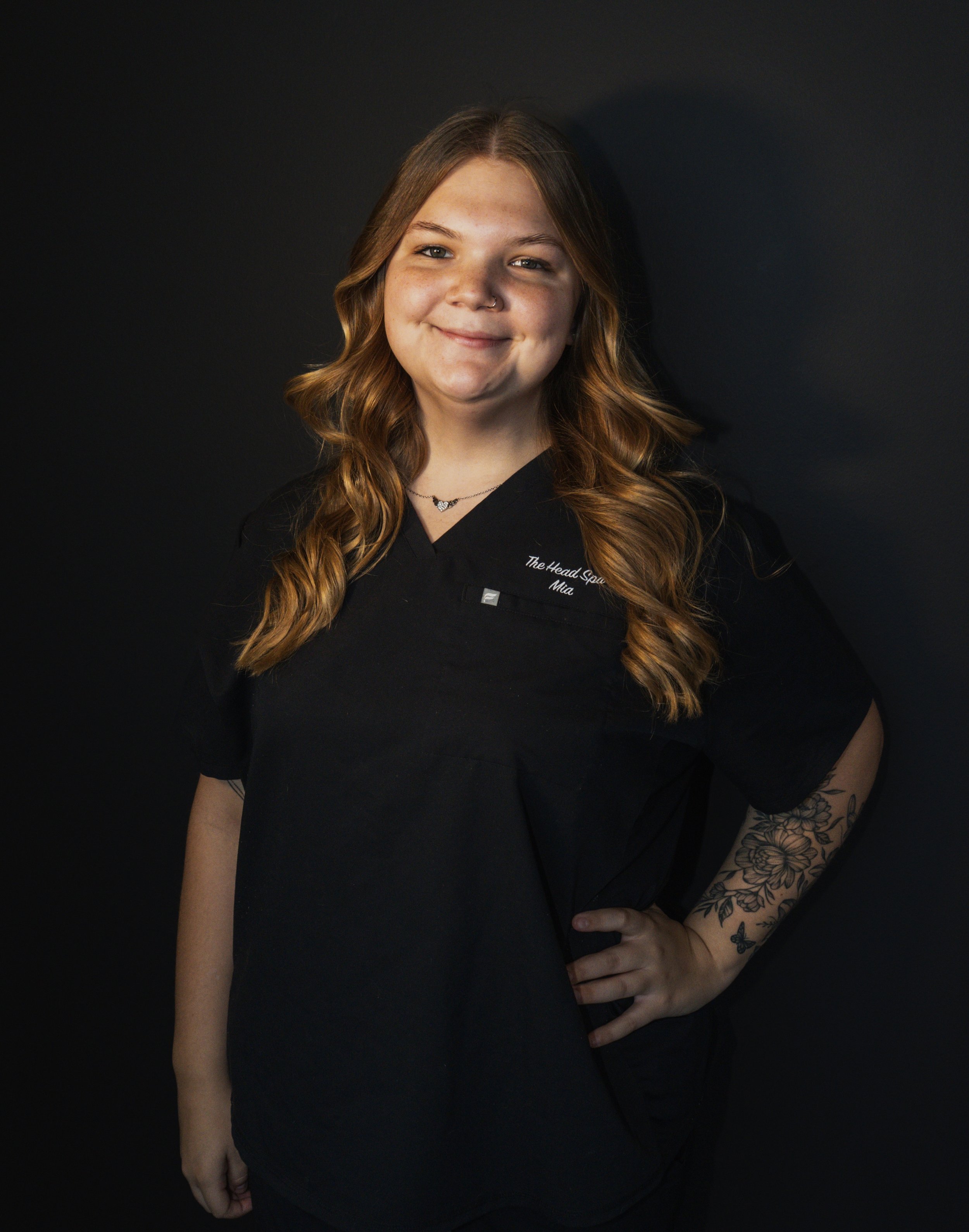 Close-up of a glass water with intricate cut patterns casting shadows onto a white surface, alongside a matching faceted glass bottle, both reflecting and refracting sunlight.