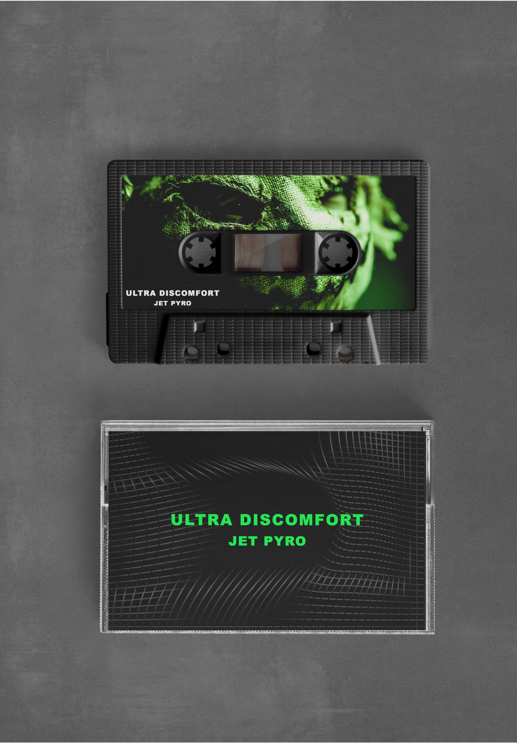 A black cassette tape with a green face image and the text 'ULTRA DISCOMFORT JET PYRO' on it, placed above a black case with green text matching the cassette's label.