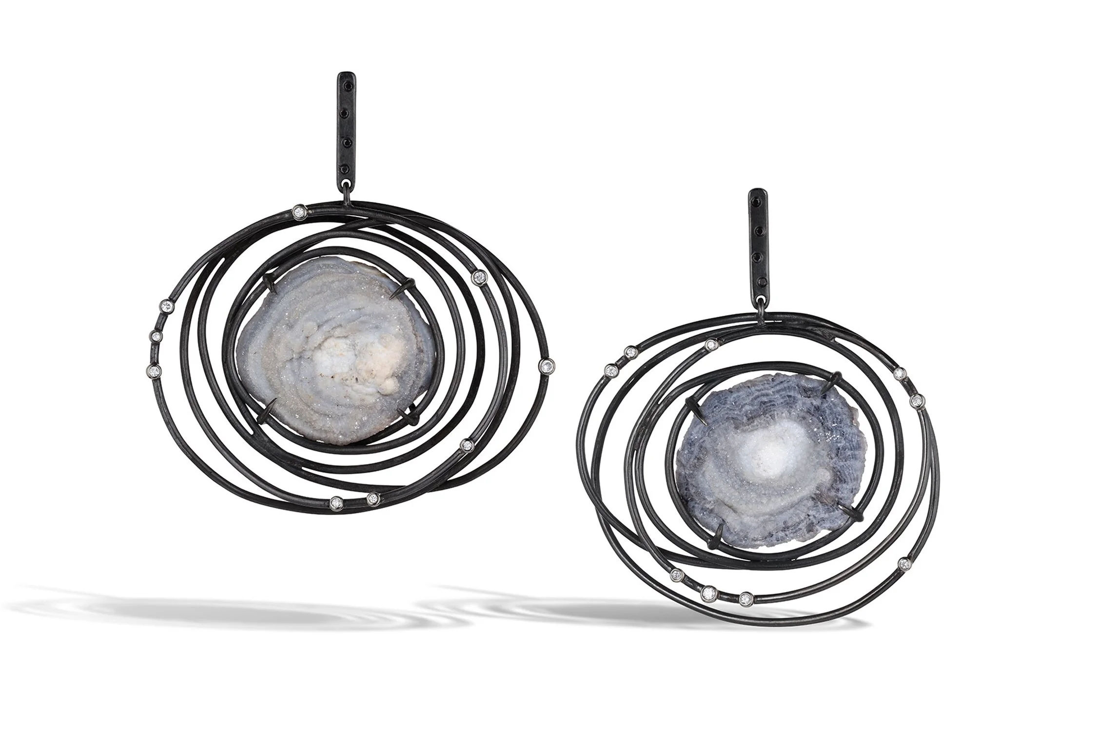 Two round black metal wall hangings with large geode stones in the center, featuring concentric circles and small decorative stones along the rings.