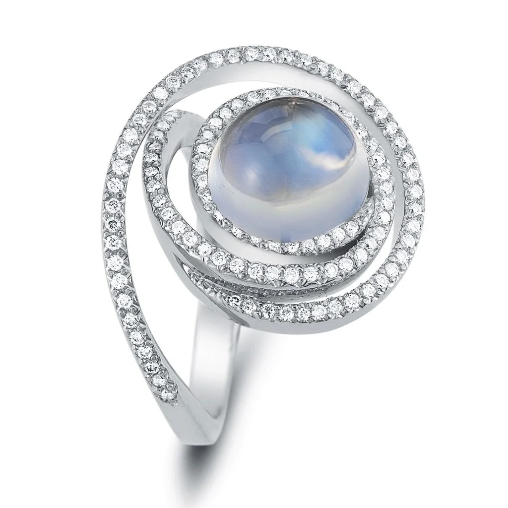Silver ring with a central moonstone surrounded by spiral rings of small diamonds.