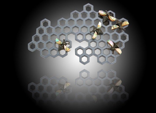 Multiple honey bees on a gray honeycomb-shaped structure against a dark background.