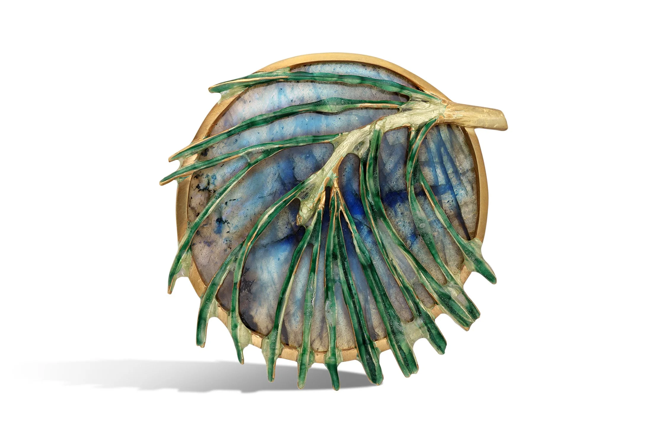 A round decorative object with a gold frame, featuring a design of green leaves on a blue marble background.