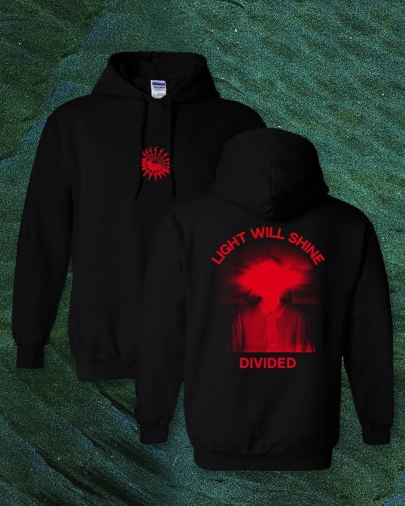 Black hooded sweatshirt with a red graphic of a person with a glowing red light on the back, and the text 'Light Will Shine' and 'Divided' in red. The front features a small red graphic of a sun-like shape.