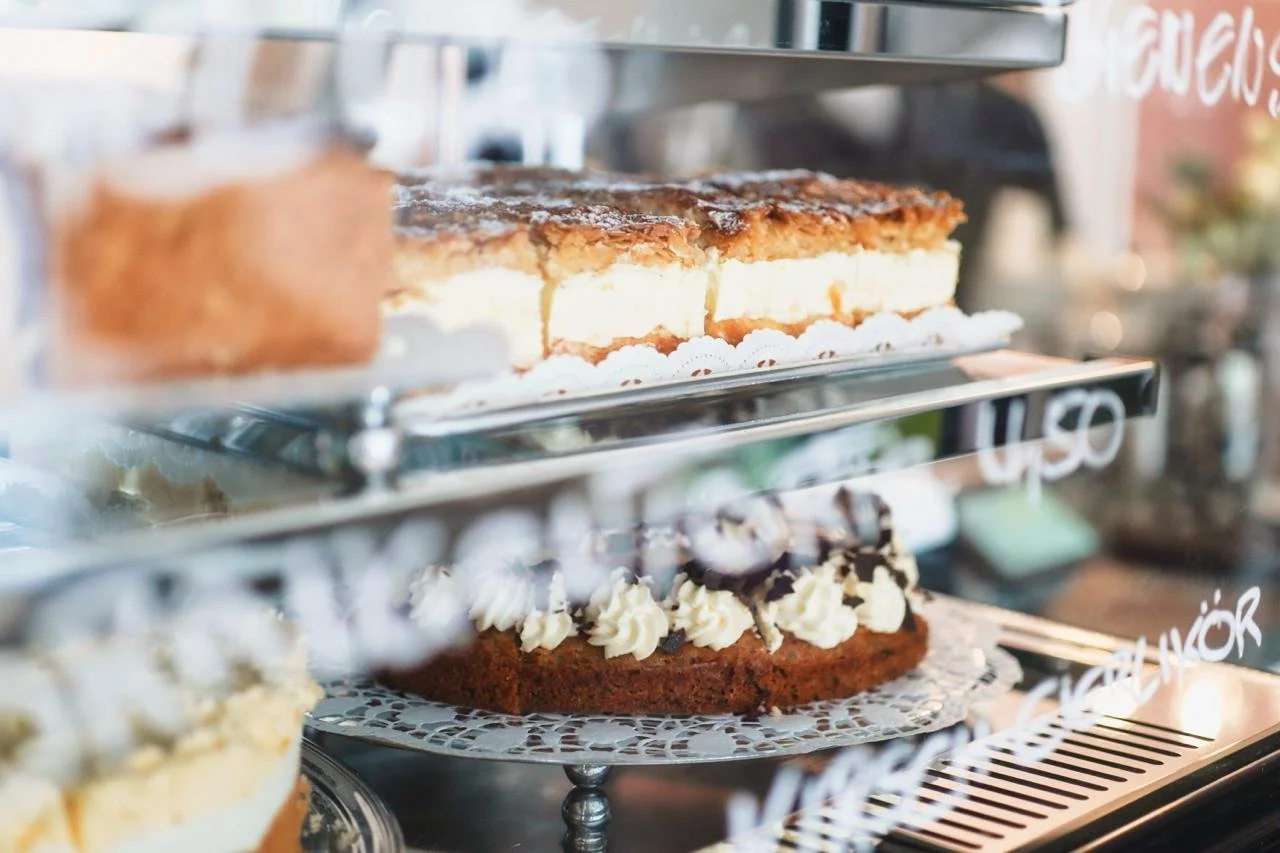 Verschiedene Kuchen in einer Kuchenvitrine des Cafés, mit Sahne, Schokoladenstückchen und Kuchen.