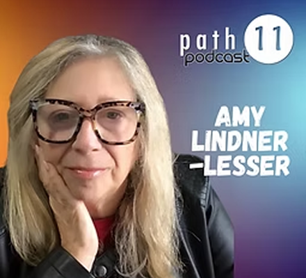 Host Amy Lindner-Lesser with long blonde hair, glasses, wearing a leather jacket, posing with her hand on her face against a colorful background, promoting the Path 11 podcast.