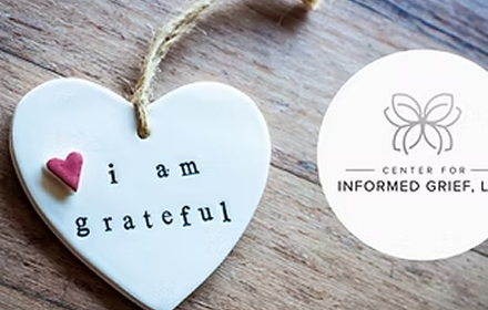 Heart-shaped white ceramic ornament with the words 'I am grateful' and a small pink heart at the top left. Rest of the message is blurred.