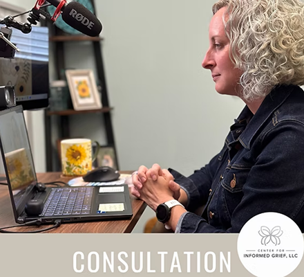 Woman with curly blonde hair sitting at a desk during a consultation, with a laptop, microphone, and sunflower-themed items in the background.
