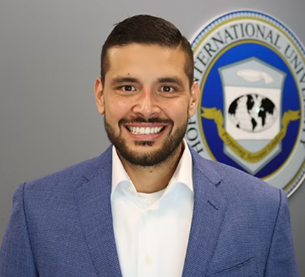 A man smiling in front of a logo that includes a graduation cap, globe, and the words 'International University.'
