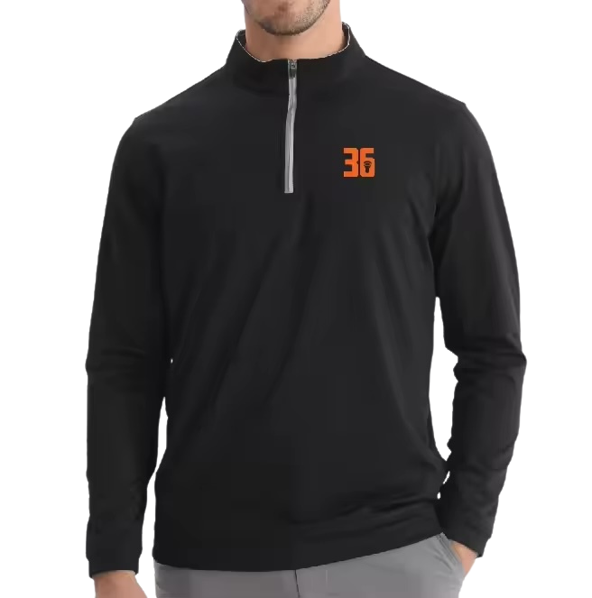 A man wearing a black athletic long-sleeve shirt with a quarter-zip collar and an orange logo with the number 36 on the left chest.