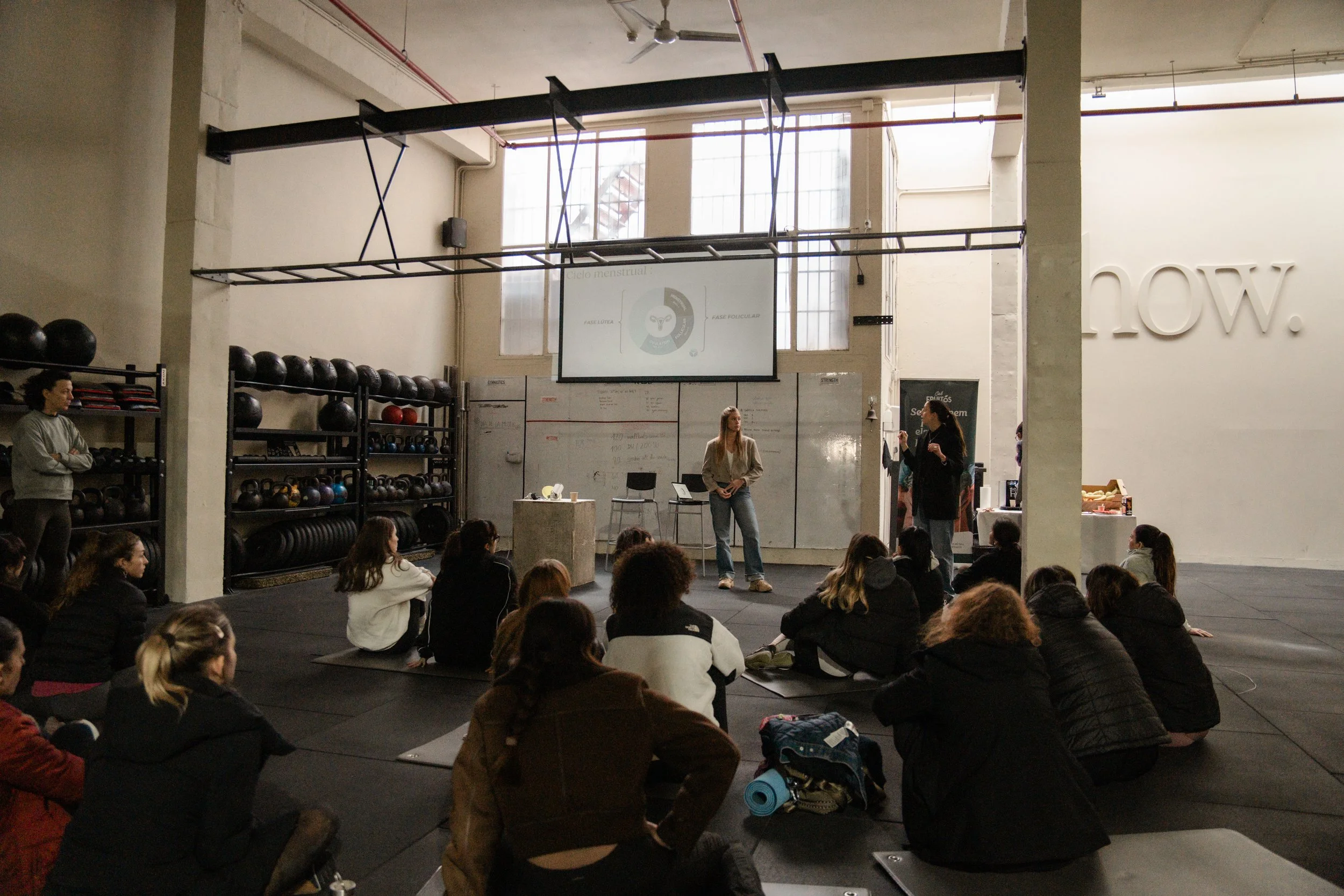 Grupo de personas en una clase de jiu-jitsu en un gimnasio, practicando técnicas en el suelo.