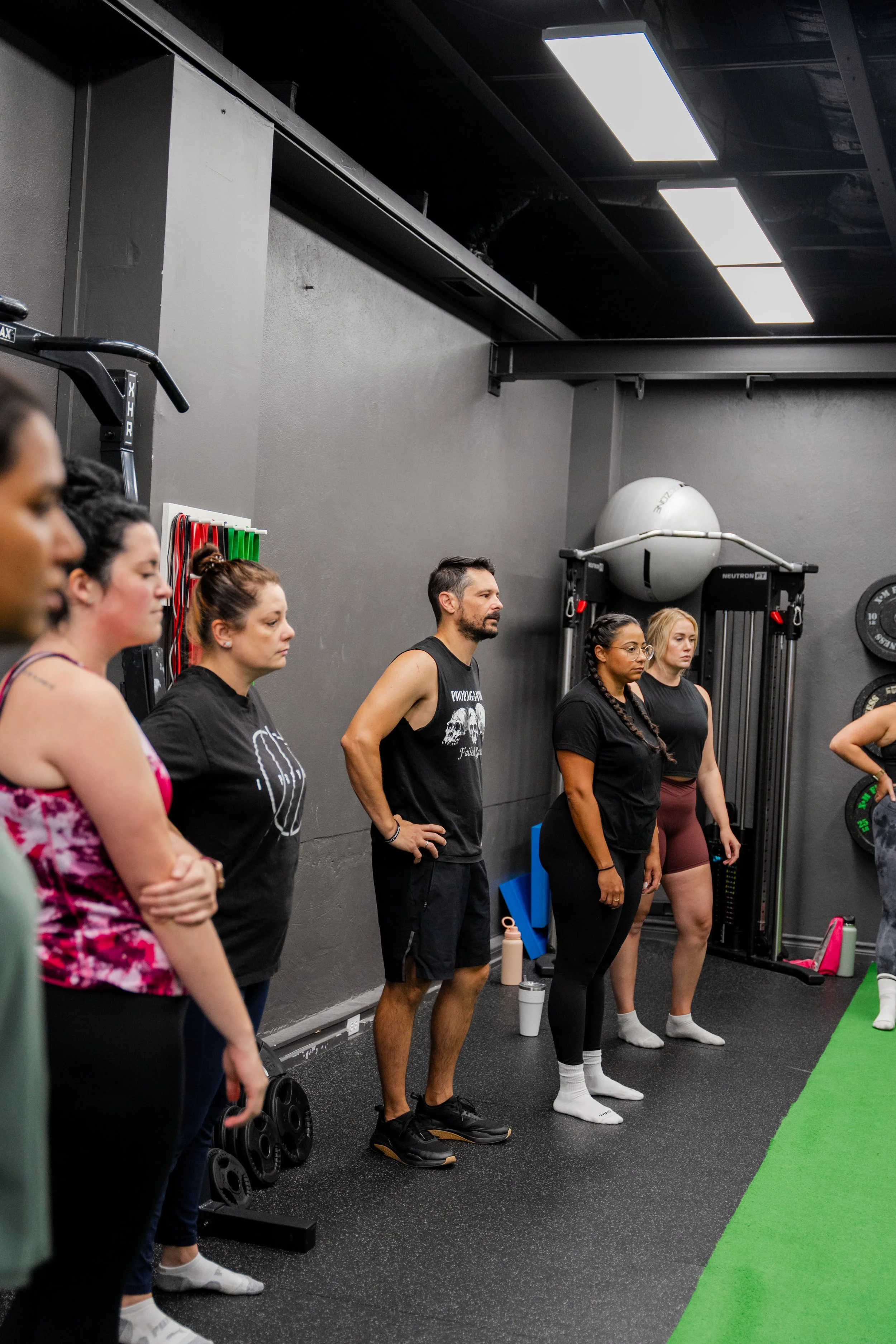 People standing with their eyes closed in a gym, listening during a fitness class.