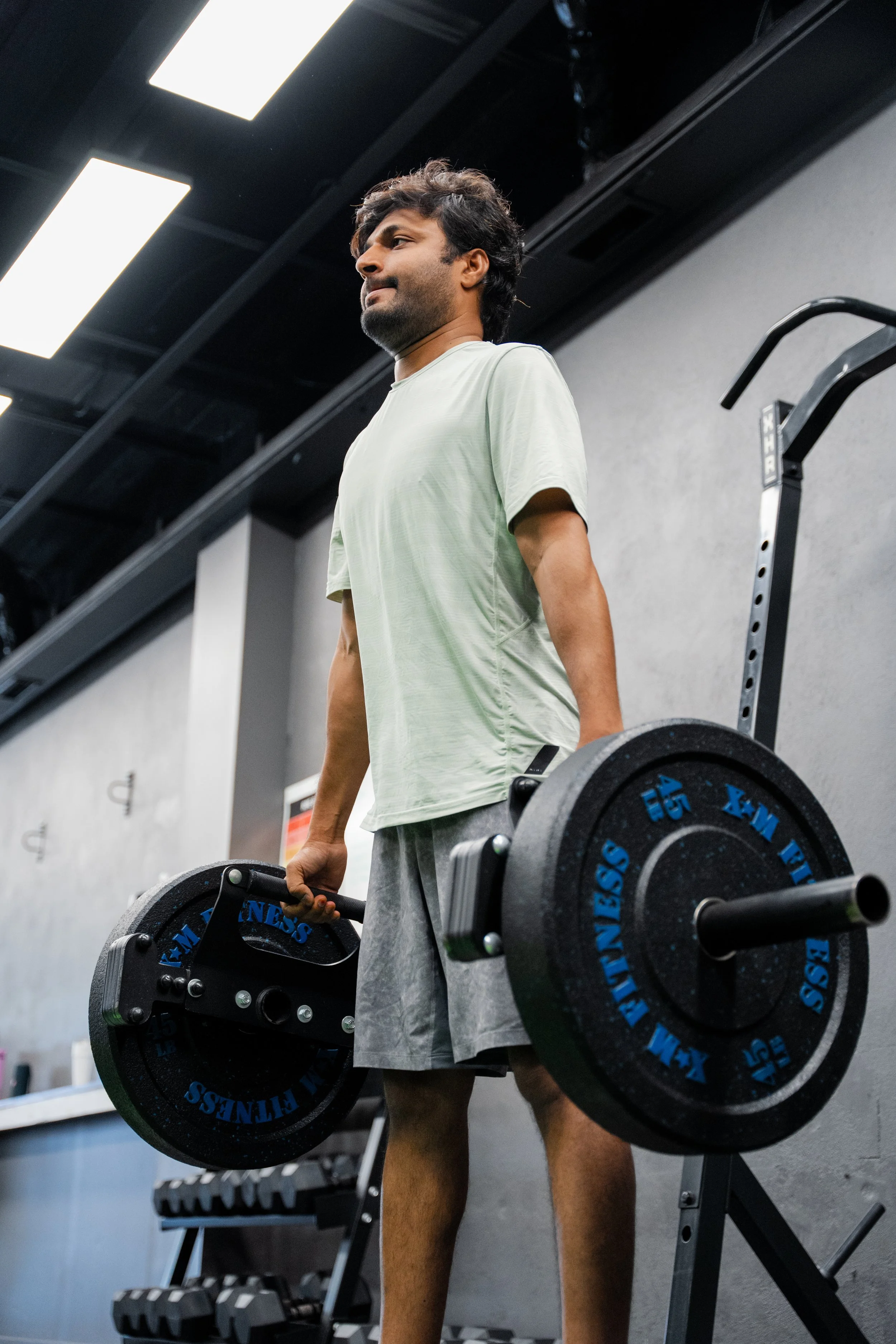 A man lifting weights with a barbell in a gym.