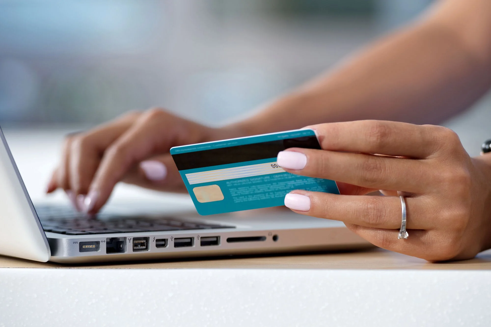 Person holding a credit card while using a laptop computer.
