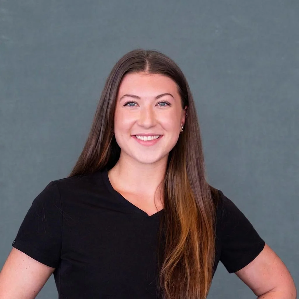 A young woman with long brown hair smiling in front of a black background with white text.