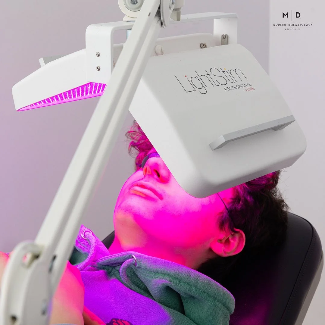 A person receiving a light therapy treatment on their face from a LightStim device in a clinic setting.