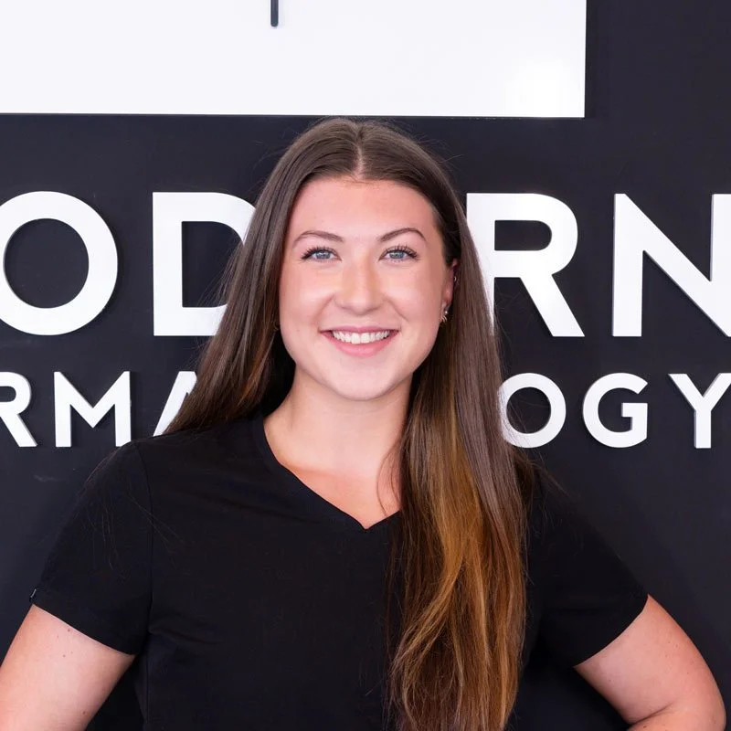 A young woman with long brown hair smiling in front of a black background with white text.
