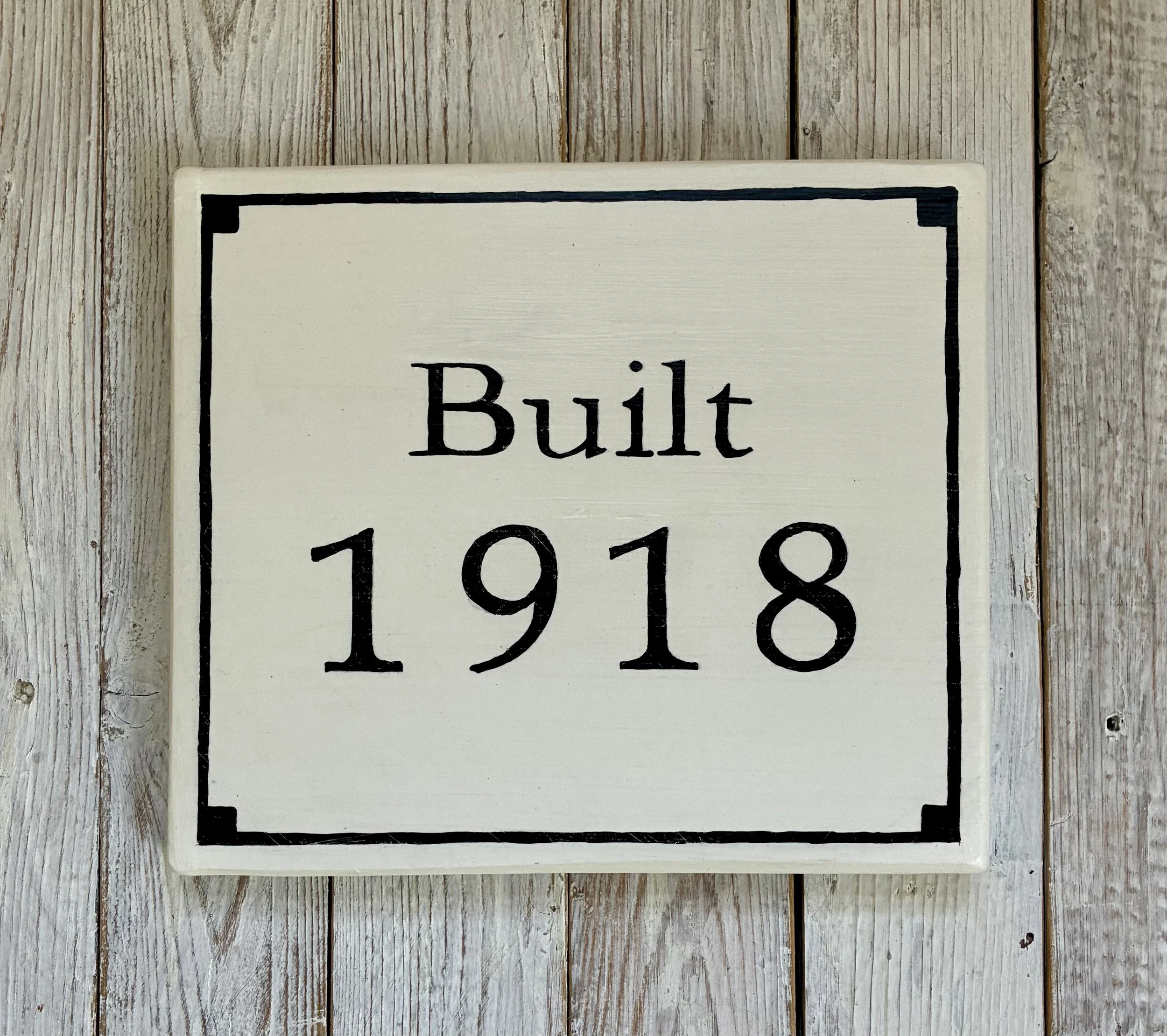 A decorative white sign with black border and text that reads "Built 1918"