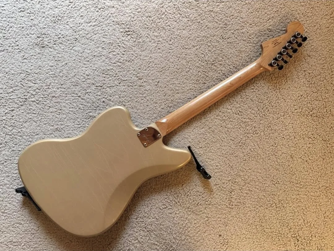 Back of an electric guitar lying on a carpeted floor.