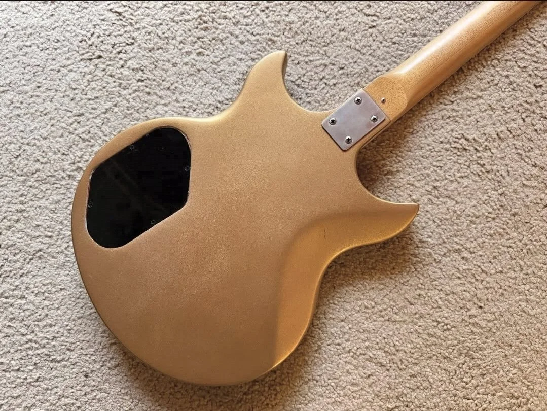 Back of a tan electric guitar lying on a beige carpet.