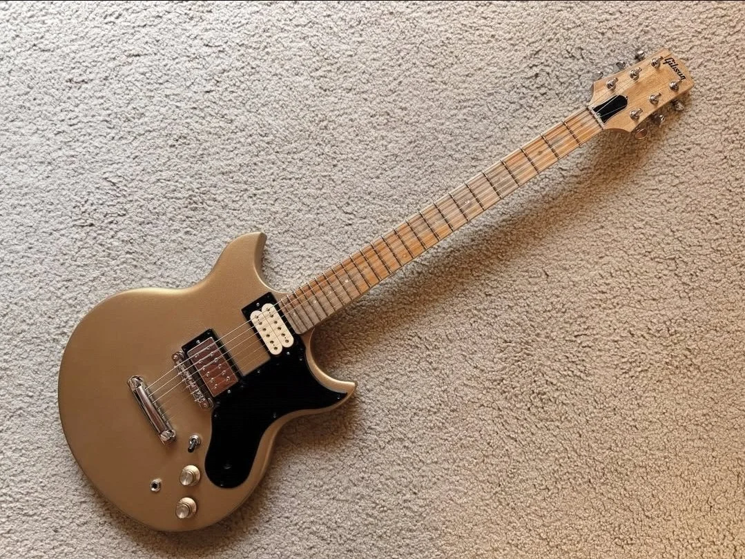 Golden electric guitar with a black pickguard lying on a carpeted floor.