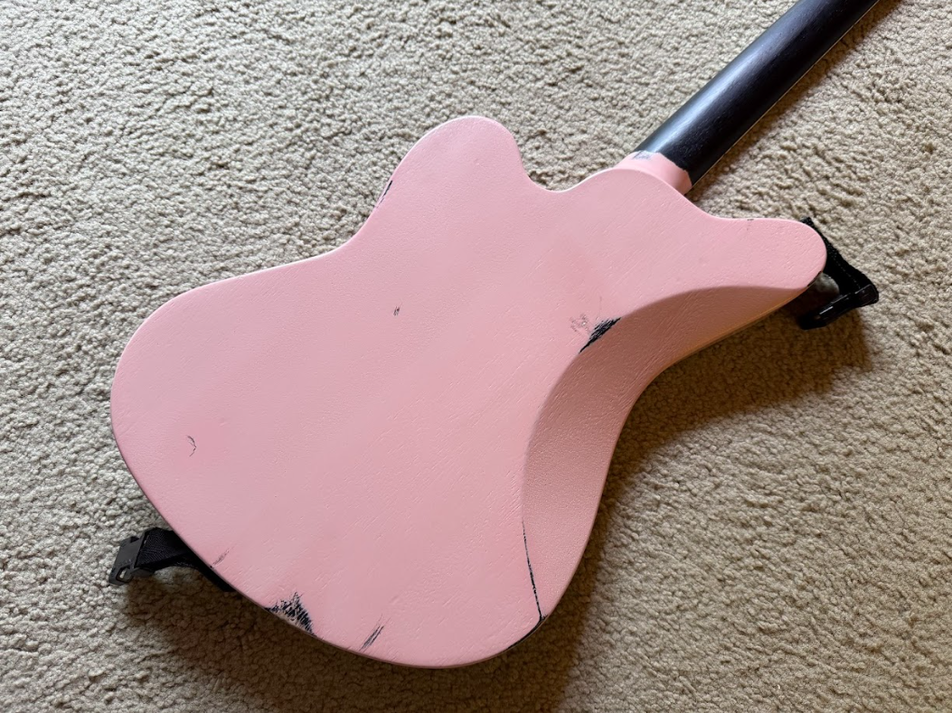 Pink wooden children's rocking toy shaped like an animal, on a beige carpet.