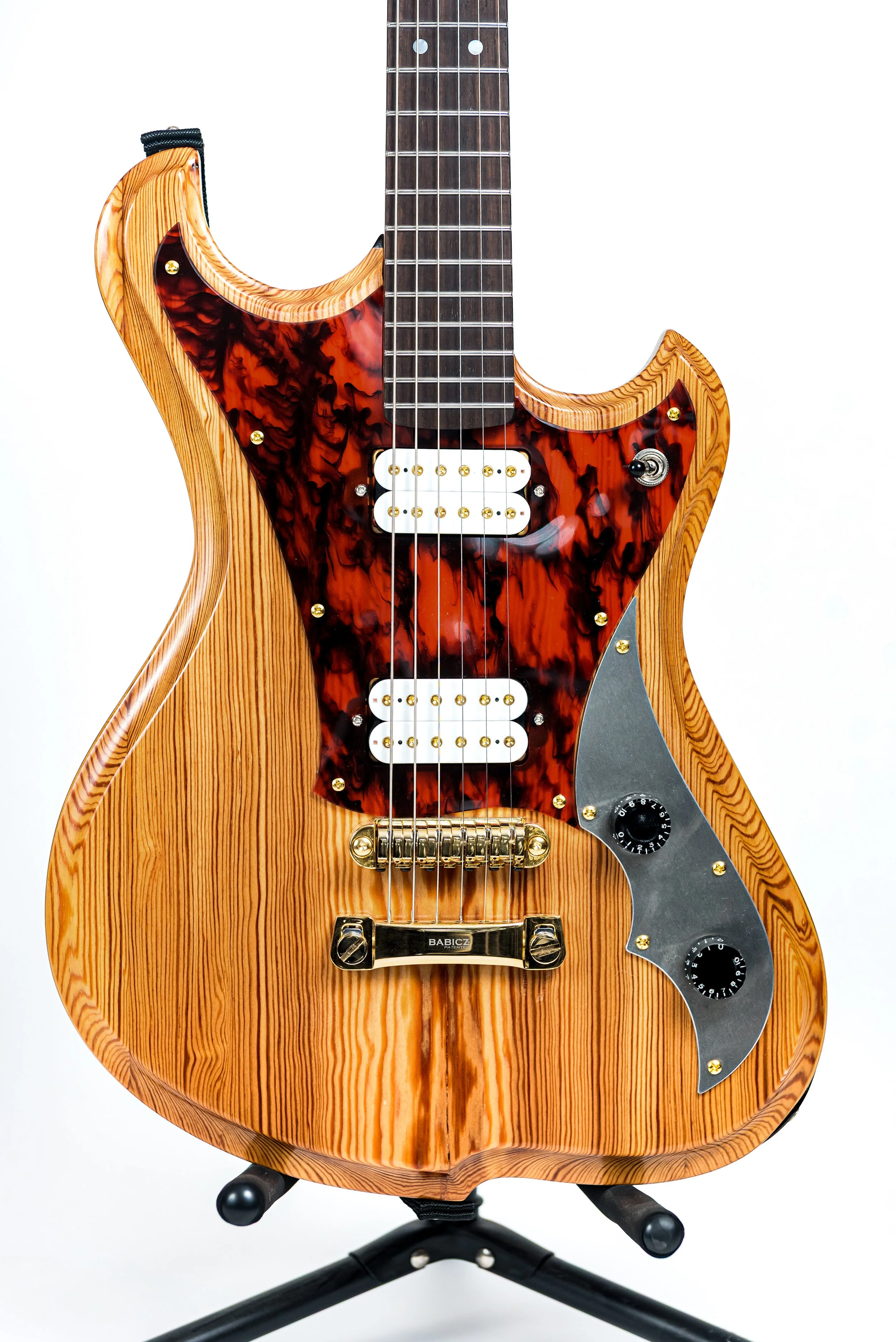 Electric bass guitar with a natural wood finish, tortoiseshell pickguard, and black control knobs on a white background.