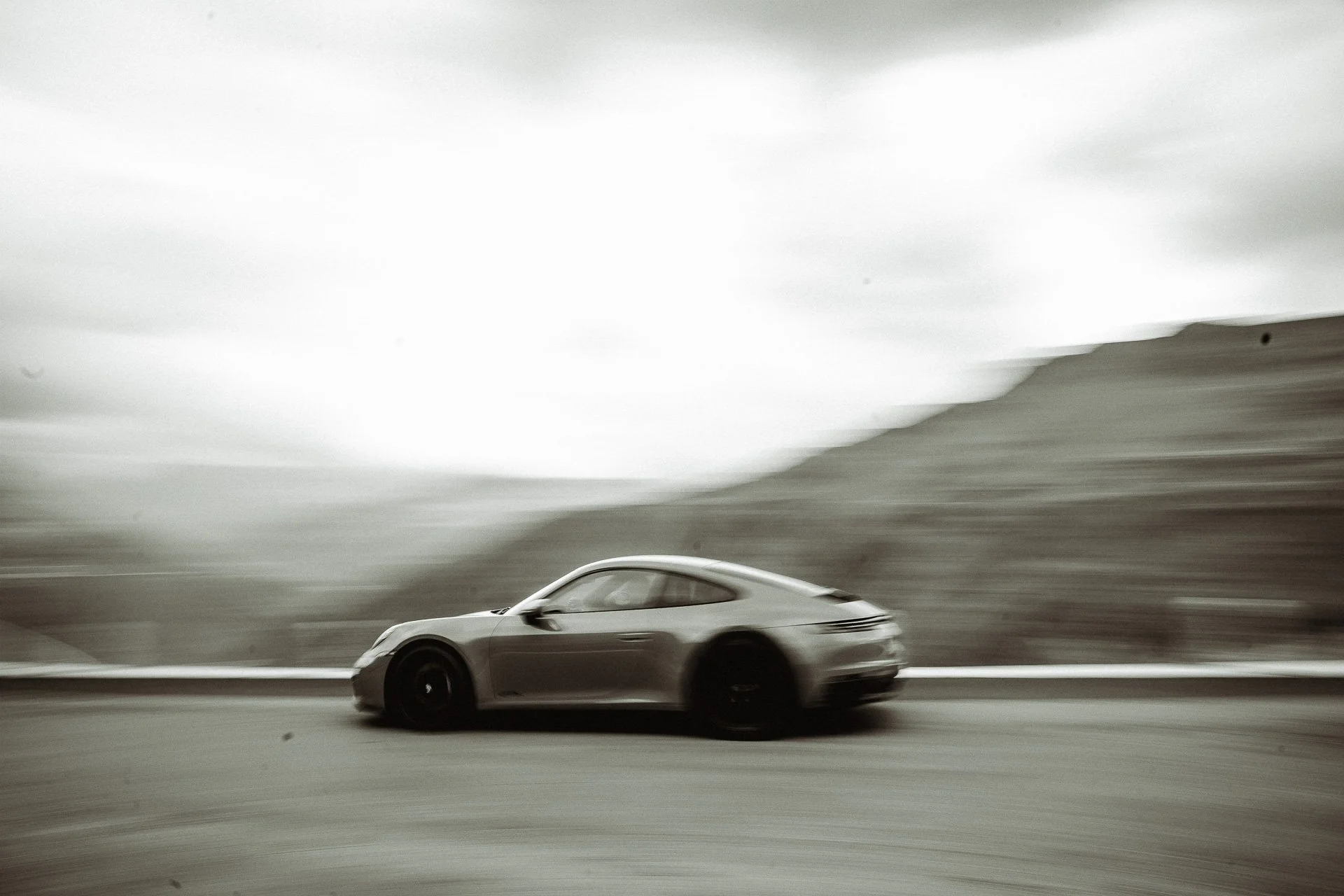 A sleek sports car driving on a road with a blurred background, creating a sense of speed.