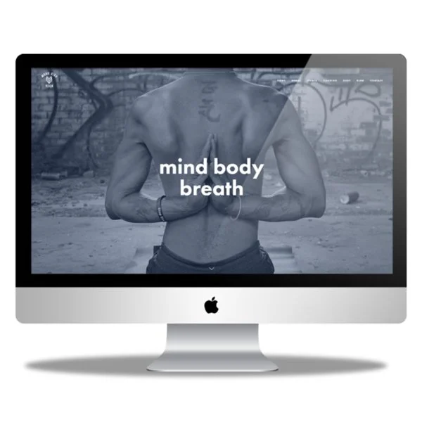 Computer monitor displaying a shirtless person with hands in a prayer position and the words "mind body breath" on the screen.