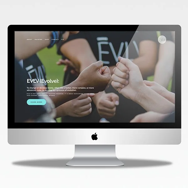 An Apple iMac computer displaying a website with a close-up image of multiple hands giving a thumbs-up gesture, some with the words 'EVOLVE' written on their shirts.
