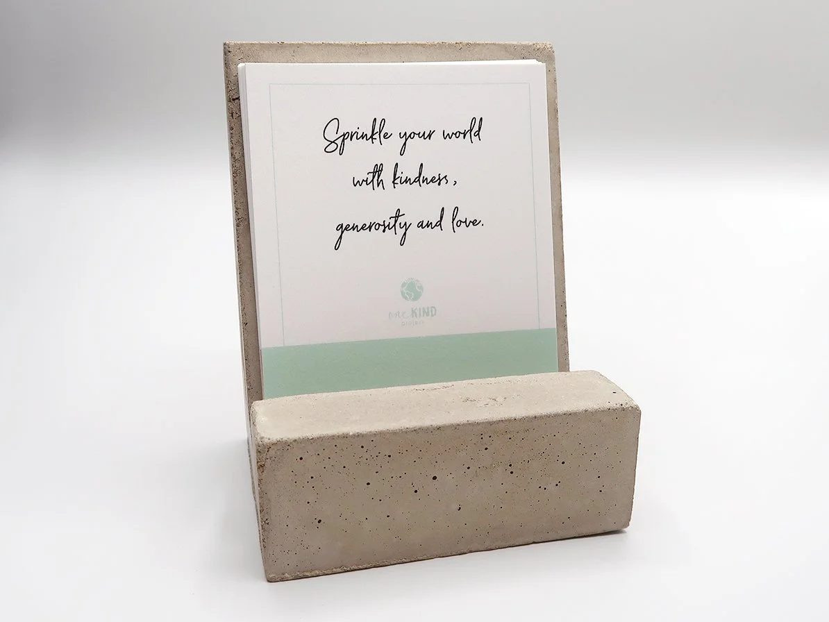Inspirational quote on a card in a concrete holder reads, 'Sprinkle your world with kindness, generosity and love.'