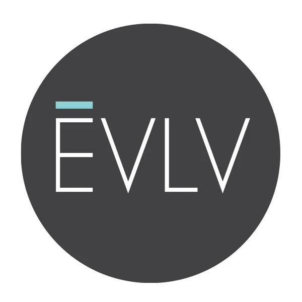 A circular logo with a dark gray background and the stylized white text 'ÉVLV' in the center, with a small light blue accent above the letter 'E'.