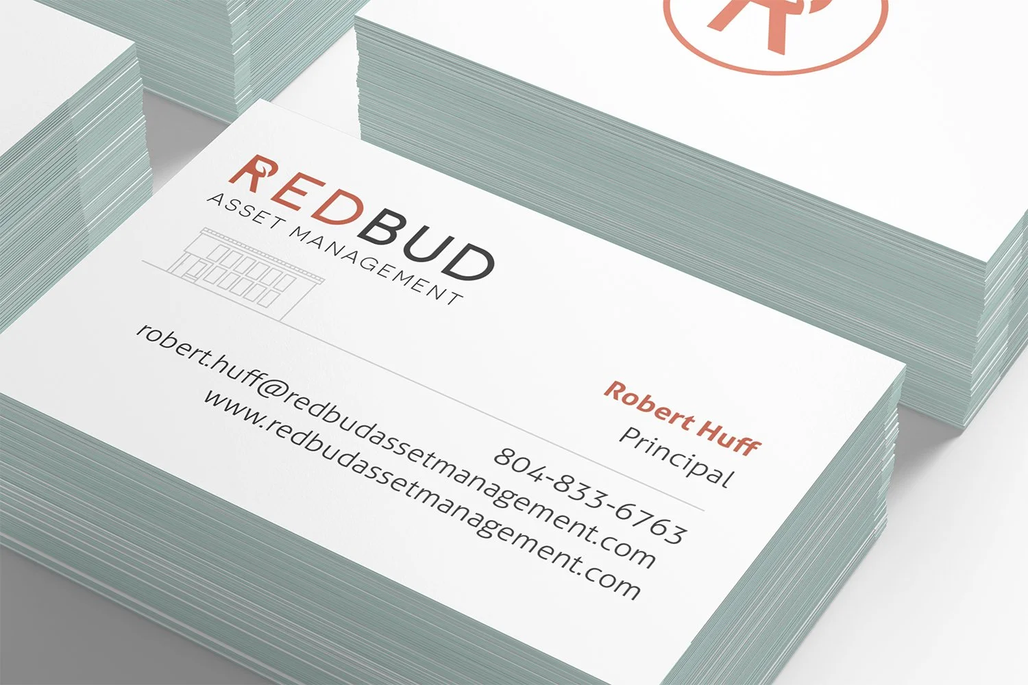 Close-up view of business cards for Red Bud Asset Management, with contact details for Robert Huff, the principal. The cards are stacked on a white surface, showcasing the logo, name, title, email, phone number, and website.