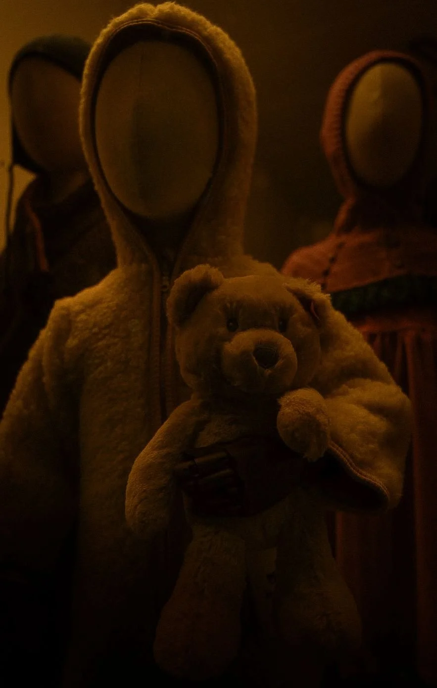Three mannequins standing quietly in a dimly lit shop window at night.