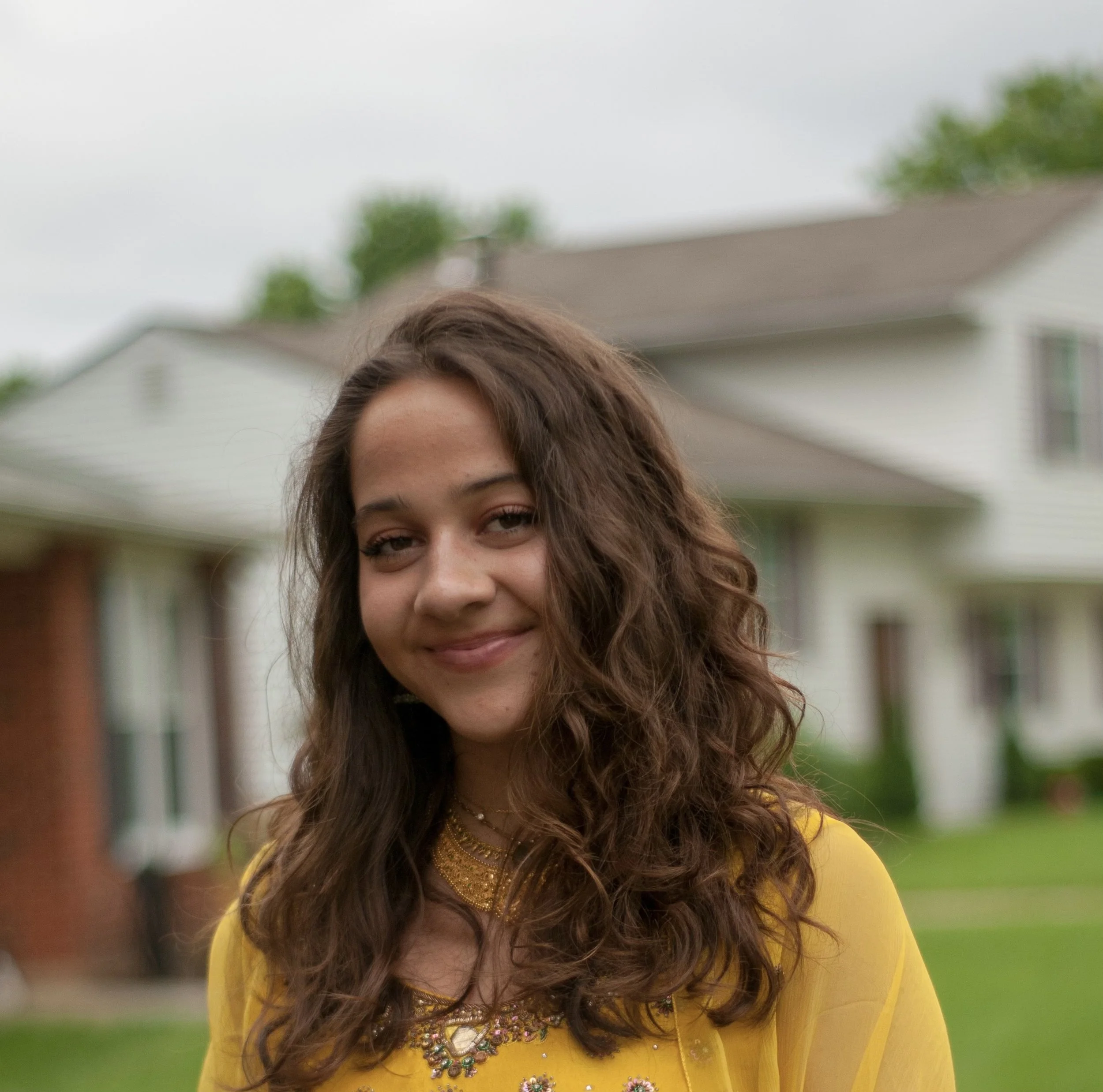 Headshot of woman with long dark hair and yellow sweater
