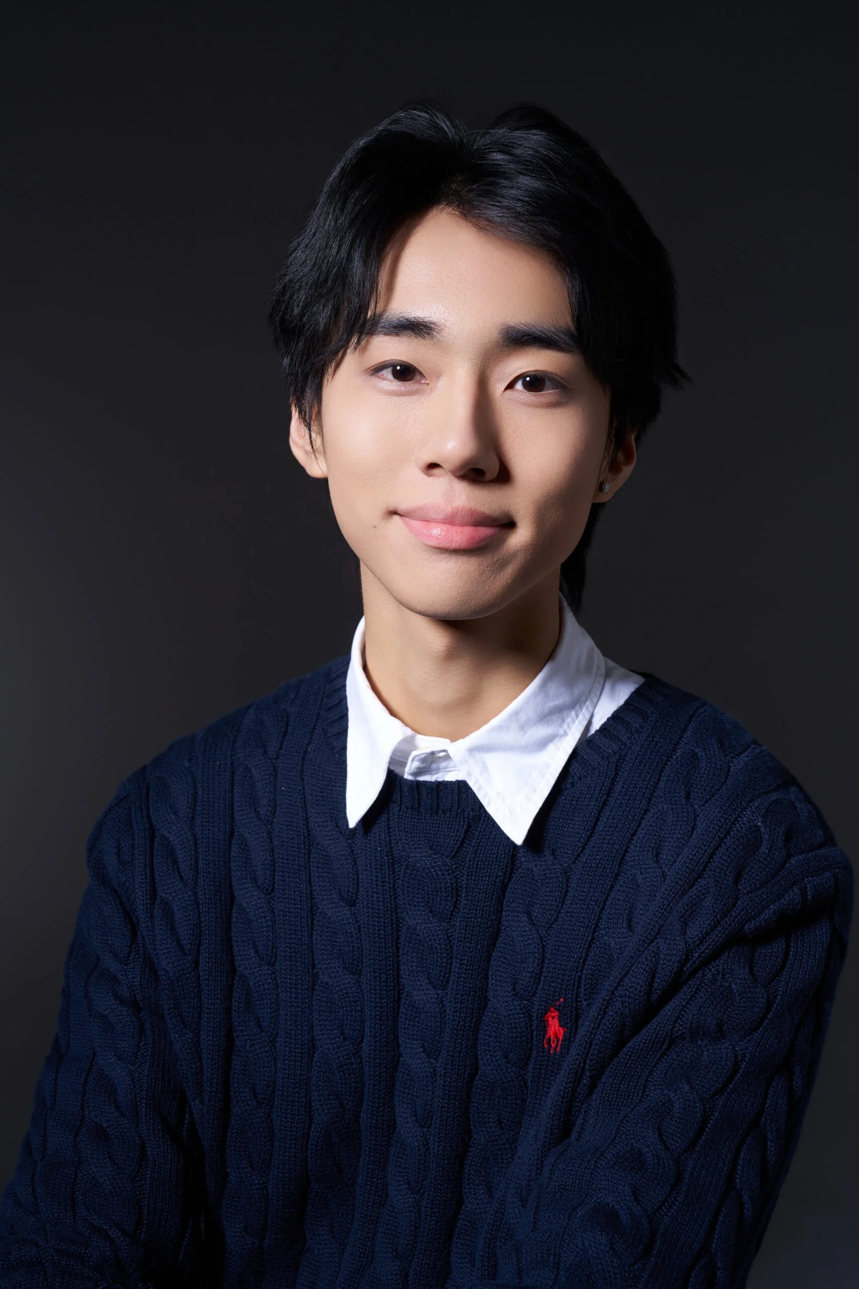 Headshot of man with dark hair, blue sweater, and light collar.