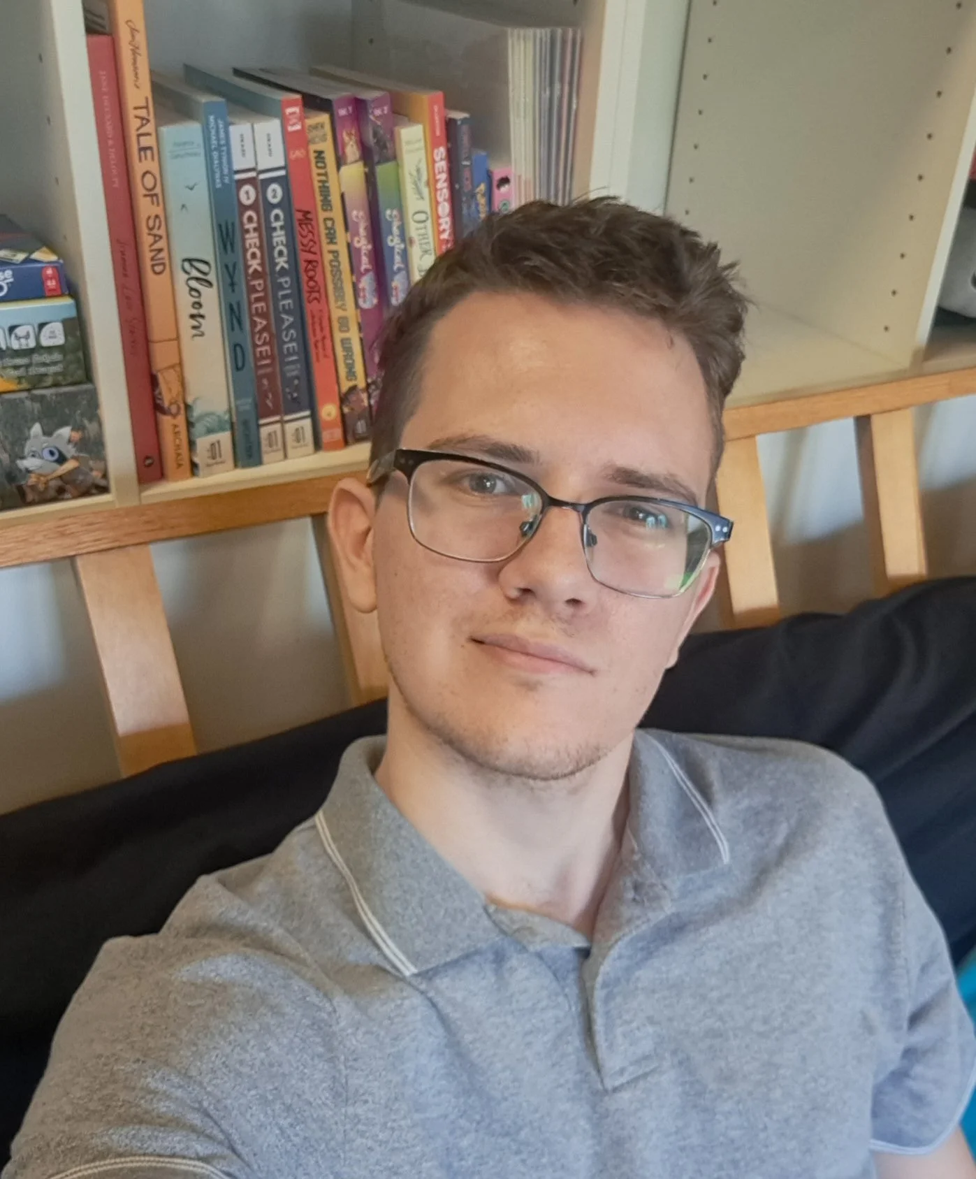 headshot of man with light and and glasses wearing a gray polo shirt.
